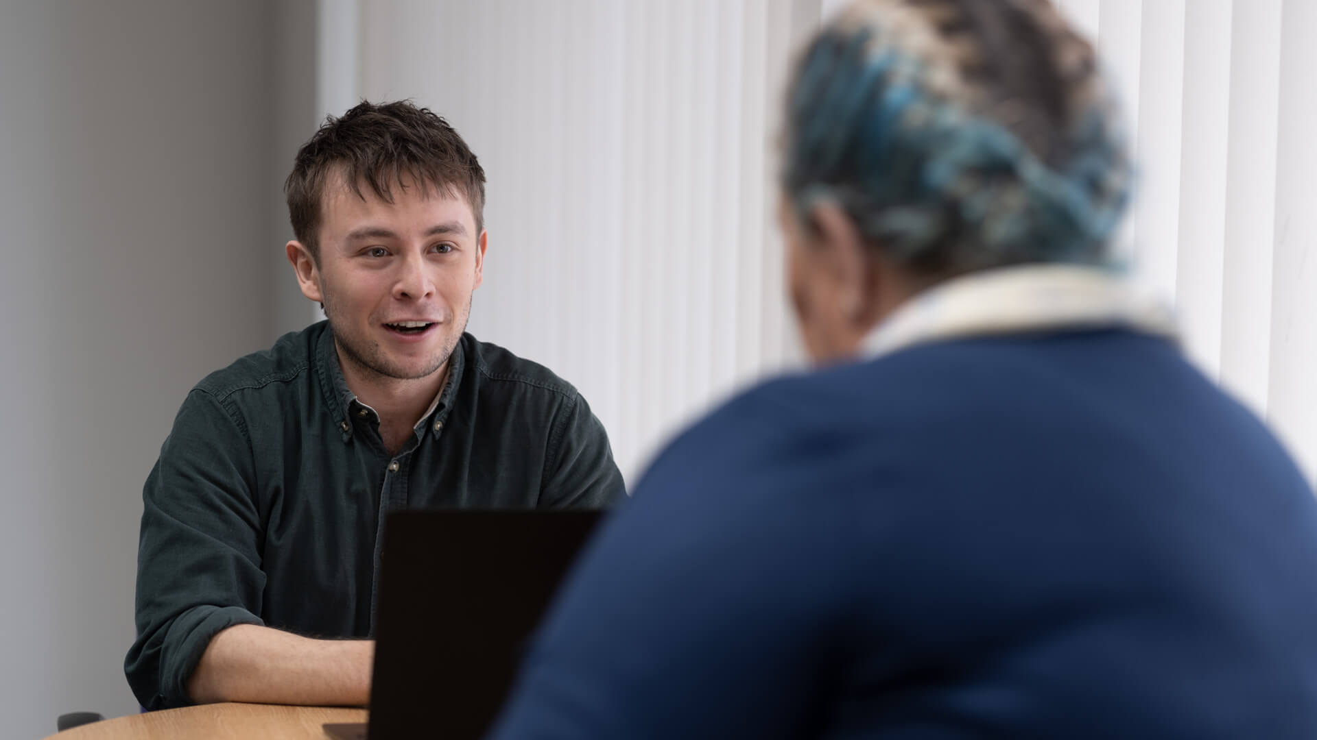 Male hmpo worker talks to their female colleague over a table