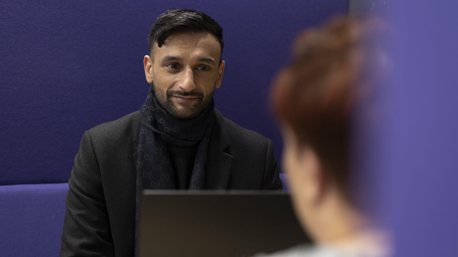 Male Home Office employee smiles whilst looking across an office.